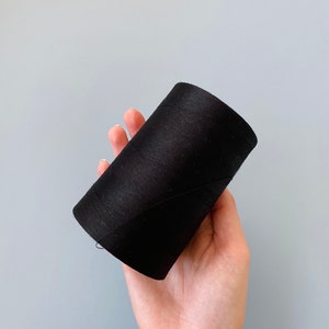 May include: A spool of black thread.