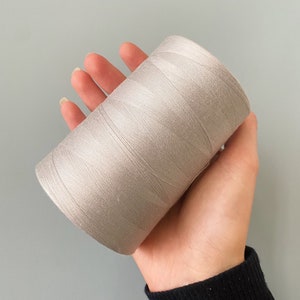 May include: A spool of light gray thread.