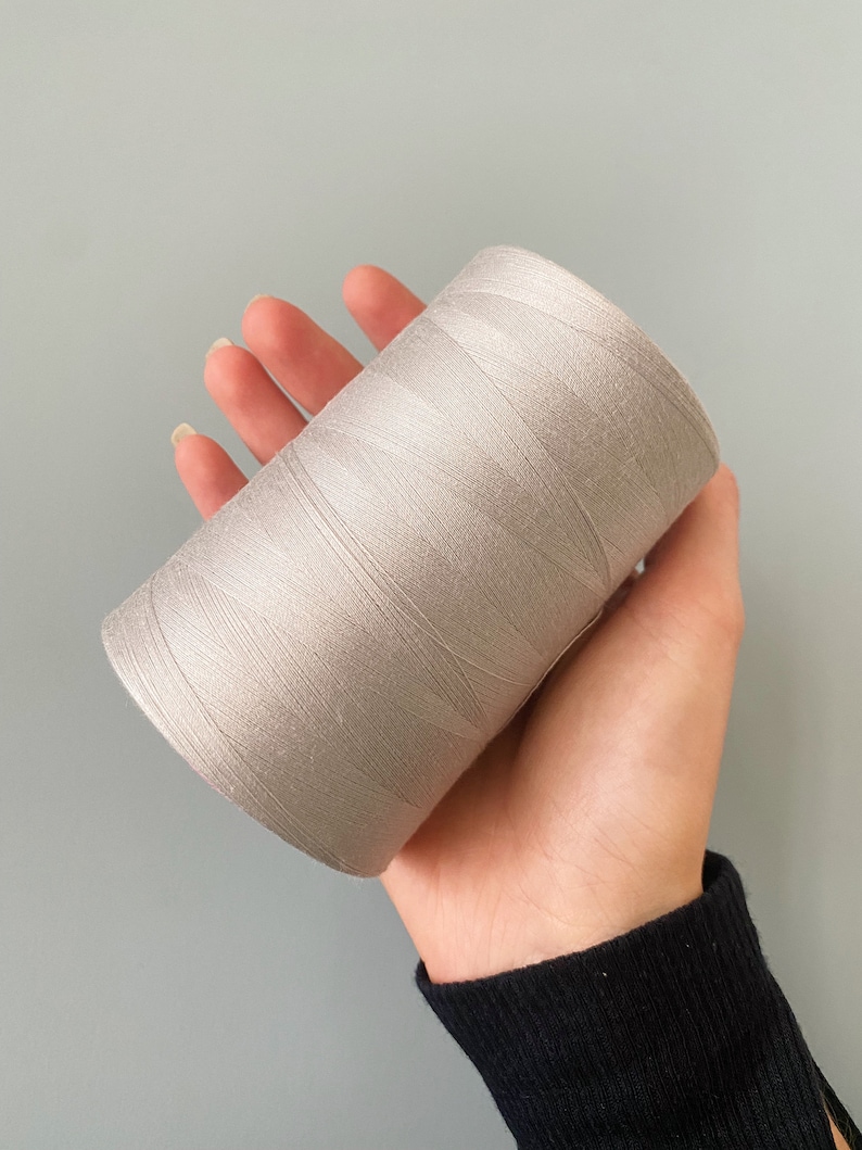 May include: A spool of light gray thread.