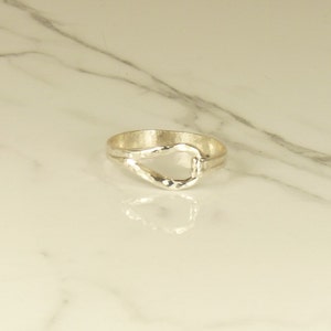 May include: A silver ring with a unique, hammered, open-loop design.