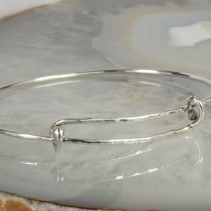May include: A silver bangle bracelet with a hammered finish and a simple clasp.