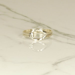 May include: A silver ring with a twisted band and a large oval opening in the center.