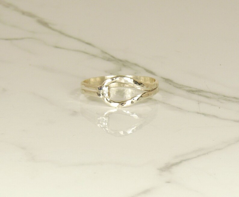 May include: A silver ring with a twisted band and a large oval opening in the center.