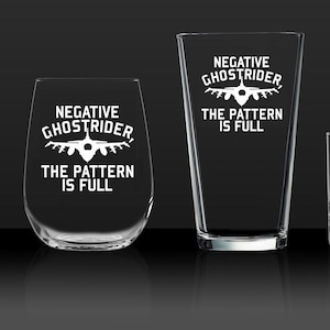 Pode incluir: Quatro copos de beber de vidro transparente de diferentes tamanhos com o texto "Negative Ghostrider, the pattern is full" e uma silhueta de um caça gravada na frente.