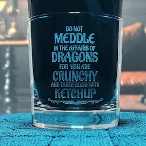 May include: A clear glass tumbler with an etched design that reads "Do not meddle in the affairs of dragons for you are crunchy and taste good with ketchup."