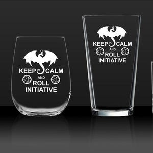 May include: Four glass drinking glasses with a white dragon design and the text "Keep Calm and Roll Initiative".