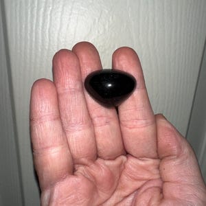 May include: A black, smooth, heart-shaped stone with a slight sheen.