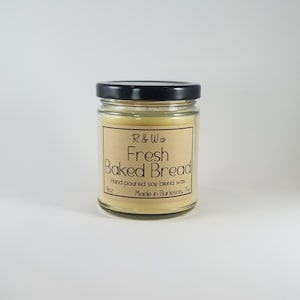 May include: A 9 ounce candle in a glass jar with a black lid. The candle is a light yellow color and has a label that says "R&W Co Fresh Baked Bread" and "Hand poured soy blend wax Made in Burleson, Tx".