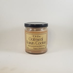 Puede incluir: Una vela de vidrio en un frasco con tapa negra. La etiqueta es marrón con texto blanco que dice "R&W  Oatmeal Raisin Cookie" y "Hand poured soy blend wax 9oz Made in Burleson, Tx".