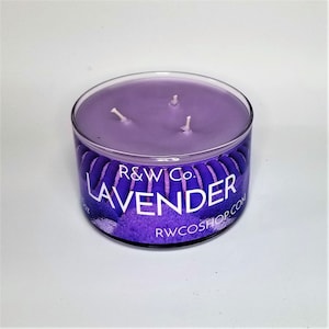 Puede incluir: Un tarro de vela de vidrio morado con tres mechas y una etiqueta que dice "R&W Co. LAVENDER RWCOSHOP.COM".