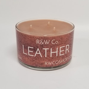 May include: A 15 oz. glass candle jar with a brown leather-textured design. The candle is labeled "R&W Co. LEATHER" and has three wicks.