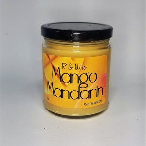 Puede incluir: Una vela de vidrio en un frasco con tapa negra. La vela es amarilla y tiene una etiqueta que dice "R & W co. Mango Mandarin" y "RWCOSHOP.COM".