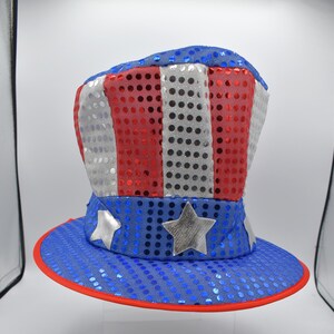 May include: A red, white, and blue sequined hat with a star design. The hat is shaped like a top hat and has a wide brim.