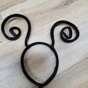 Pode incluir: Faixa de cabe&ccedil;a preta com duas orelhas enroladas, provavelmente para um traje ou uma festa.