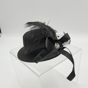 May include: A black hat with a black feather and a black ribbon with a white pearl accent.