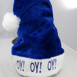 May include: A blue Santa hat with a white pom-pom and the words "OY! OY! OY!" embroidered in white on the brim.