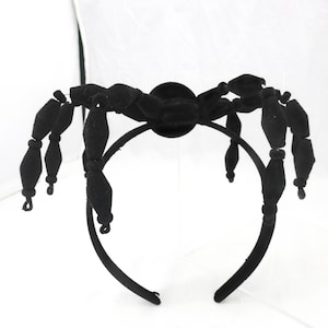 May include: Black velvet spider headband with eight legs. The spider is attached to a black headband.