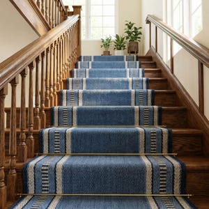May include: A staircase with blue and white patterned stair runners. The runners have a striped design and are secured with brass rods. The wooden stairs and handrails are a warm brown color, and plants are visible on the landing.