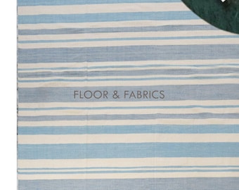 May include: A blue and white striped rug with a fringed edge. The rug is made of a soft, woven material and has a subtle sheen. The rug is perfect for adding a touch of coastal style to any room.