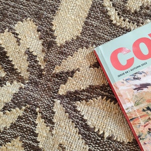 May include: A close-up of a brown and beige woven rug with a magazine titled "Co. Issue 68 | Autumn 2022" on top of it.