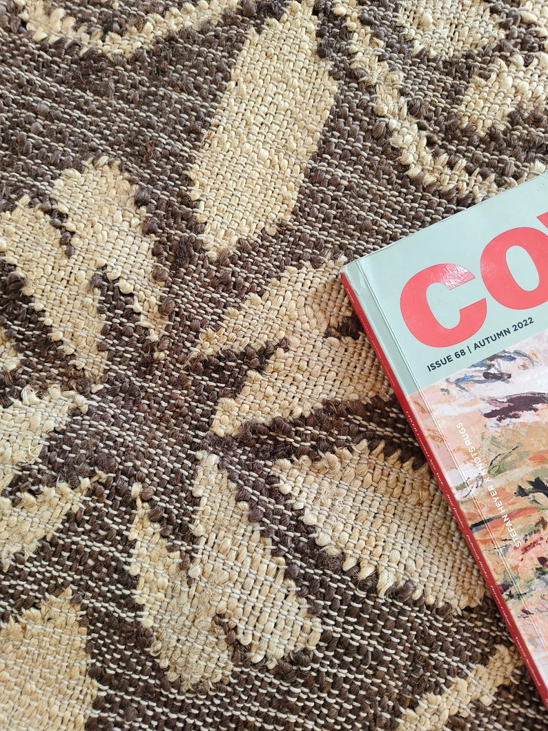 May include: A close-up of a brown and beige woven rug with a magazine titled "Co. Issue 68 | Autumn 2022" on top of it.
