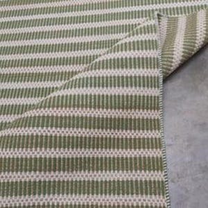 May include: Close-up of a green and white striped rug with a woven texture. The rug is folded over, showing the underside.