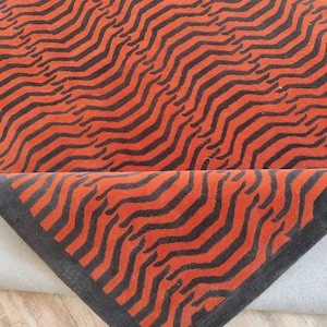May include: A red and black area rug with a wavy pattern. The rug has a black border.