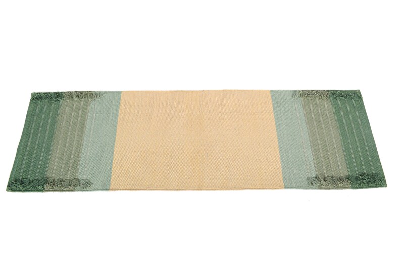 May include: A rectangular woven rug with a light beige center and green and blue stripes on the ends. The rug has a fringed edge.