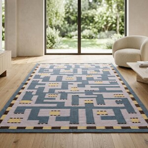 May include: A rectangular area rug featuring a geometric maze pattern in shades of blue, light gray, and yellow. The border consists of a repeating checkered design in dark brown and yellow, framing the central interlocking linear motif.