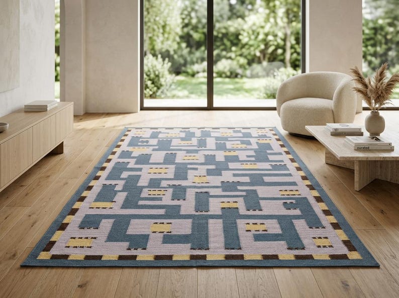 May include: A rectangular area rug featuring a geometric maze pattern in shades of blue, light gray, and yellow. The border consists of a repeating checkered design in dark brown and yellow, framing the central interlocking linear motif.