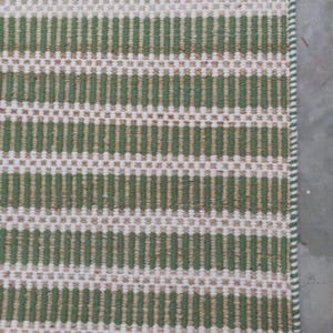 May include: A green and white striped woven rug with a subtle texture. The rug has a simple design and is made of natural fibers.