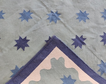 May include: A blue and white woven rug with a star pattern. The rug has a white border with a scalloped edge.