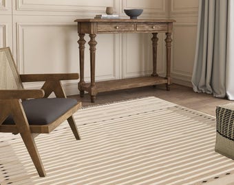 May include: A beige and black striped rug with a geometric pattern. The rug is in a room with a wooden console table and a chair.