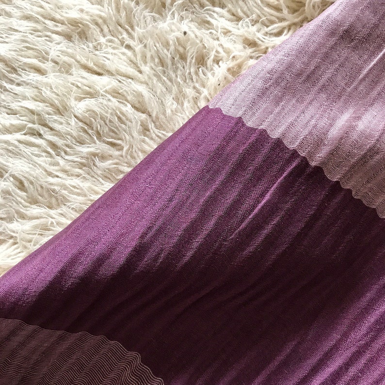 May include: A purple and pink fabric with a textured pattern. The fabric is folded in half and the pink side is on top.