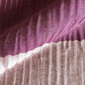 May include: A close-up of a fabric with two different textures. The top half is a deep purple with a subtle ribbed pattern. The bottom half is a lighter, more textured fabric with a subtle sheen.