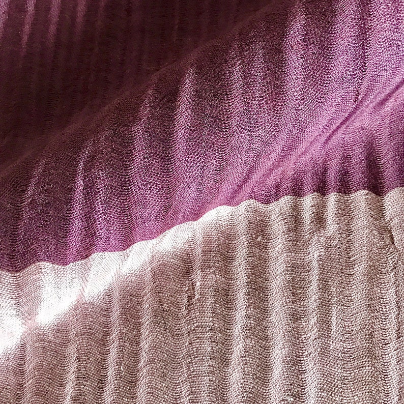May include: A close-up of a fabric with two different textures. The top half is a deep purple with a subtle ribbed pattern. The bottom half is a lighter, more textured fabric with a subtle sheen.