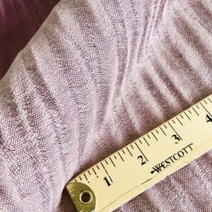 May include: Close-up of a soft, textured, mauve fabric with a wooden ruler measuring 4 inches. The ruler has the text "WESTCOTT" printed on it.