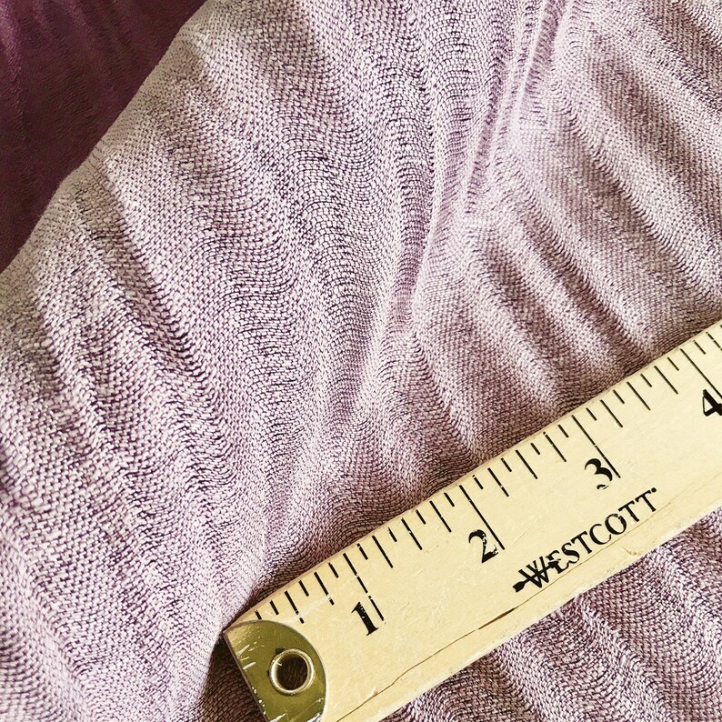 May include: Close-up of a soft, textured, mauve fabric with a wooden ruler measuring 4 inches. The ruler has the text "WESTCOTT" printed on it.