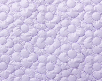May include: A light purple quilted fabric featuring a repeating pattern of stitched flowers. The material has a smooth, slightly shiny texture with raised, padded sections that define the floral shapes across the entire surface area.