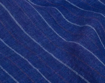 May include: Close-up of a blue fabric with white vertical stripes. The fabric has a slightly wrinkled texture, with the stripes appearing to curve gently across the surface. The color is a deep, saturated blue.