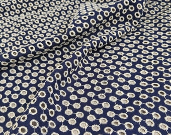 May include: Navy blue fabric with a repeating pattern of white embroidered circles. The fabric is draped, showing the texture and design. This textile could be used for clothing or home decor.