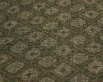 May include: Close-up of a textured fabric with a repeating pattern of diamond shapes. The diamonds are outlined in a dark red color and filled with a muted green and tan color. The background is a darker green.