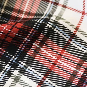 K&ouml;nnte beinhalten: Nahaufnahme eines Stoffes mit klassischem Karomuster. Das Design zeigt eine Kombination aus roten, schwarzen, wei&szlig;en und hellblauen Streifen. Der Stoff hat ein strukturiertes Aussehen, wobei das Muster ein Gef&uuml;hl von Tiefe und visuellem Interesse erzeugt.