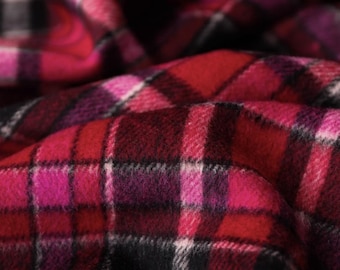 May include: A soft fabric featuring a classic tartan pattern in vibrant shades of red, deep magenta, and black. The textile displays a woven texture with intersecting horizontal and vertical lines, creating a repeating checkered design across the surface.