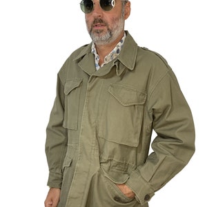 May include: A green military-style jacket with a button-up front, four pockets, and a drawstring waist.