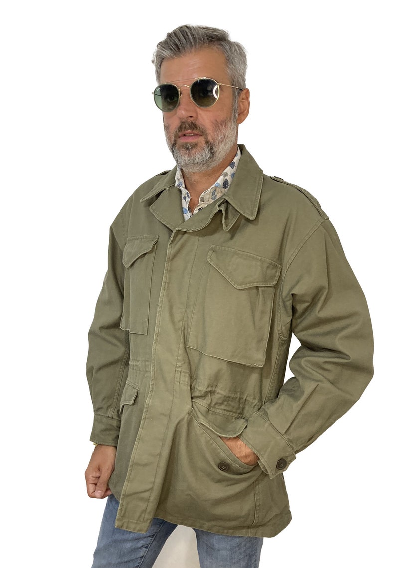 May include: A green military-style jacket with a button-up front, four pockets, and a drawstring waist.