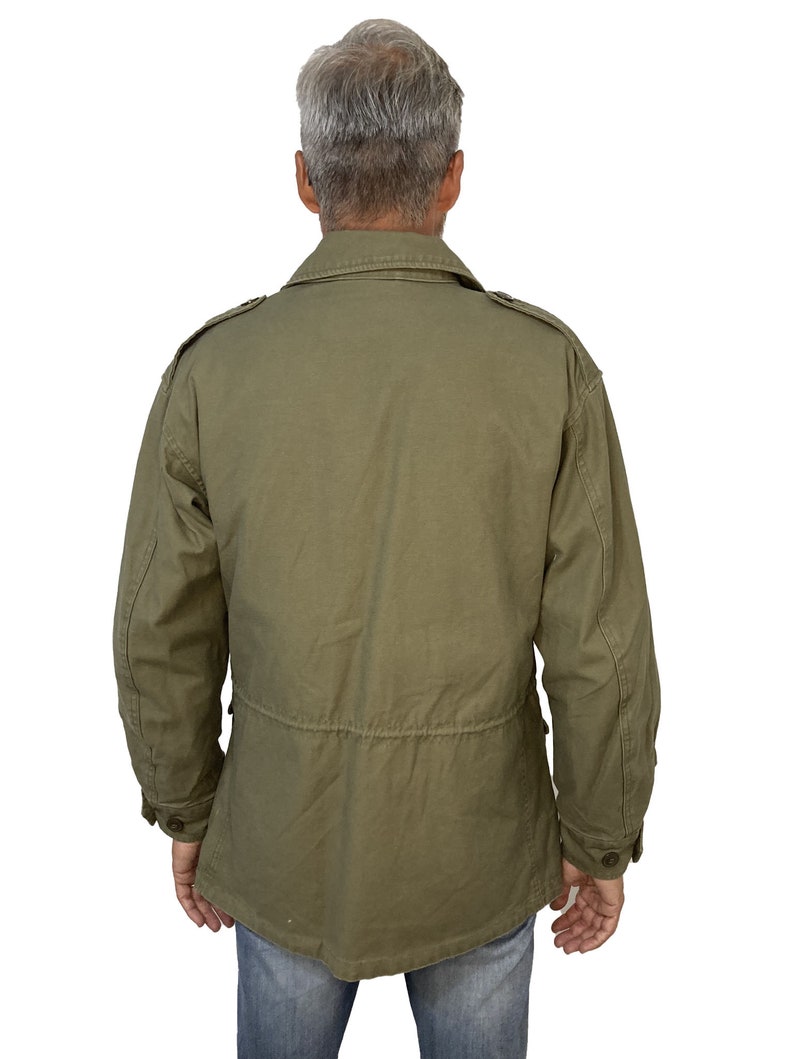 May include: A green utility jacket with a button-up front and flap pockets. The jacket has a drawstring waist and a relaxed fit.