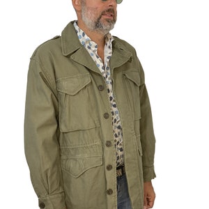 May include: A green utility jacket with a button closure and multiple pockets. The jacket has a relaxed fit and is made of a durable fabric.