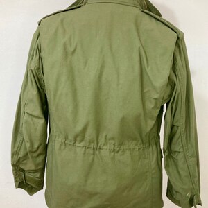 May include: A green military-style jacket with a zipper closure and a drawstring waist.