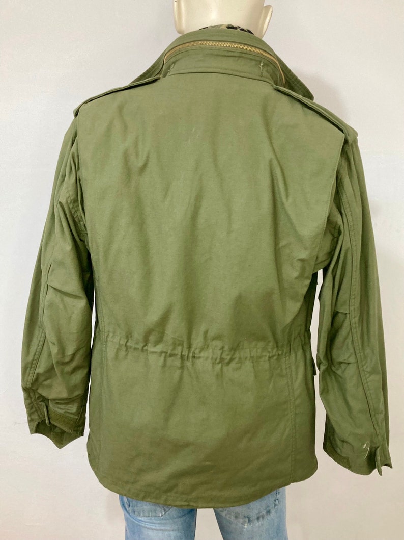 May include: A green military-style jacket with a zipper closure and a drawstring waist.
